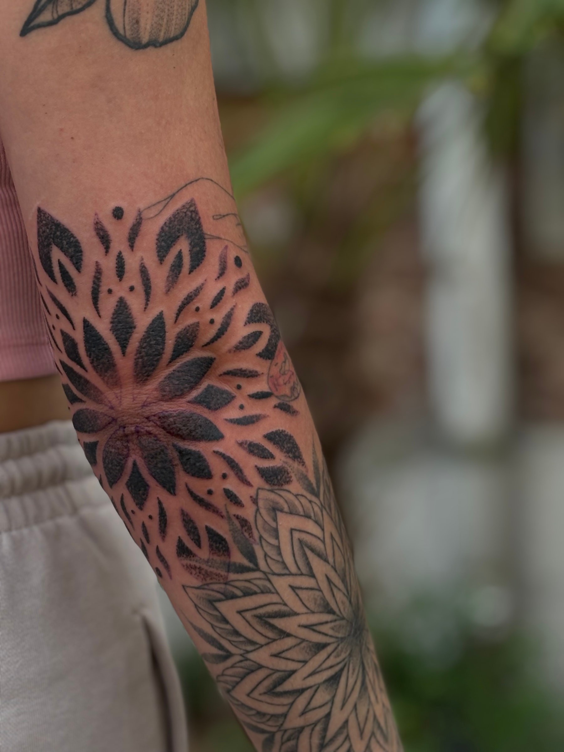 Projet en blackwork ornemental réalisé au coude, où aplats profonds et réserves dessinent une rosace graphique inspirée des mandalas.